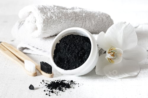Preview: Close up of black natural teeth whitening powder and toothbrushes.