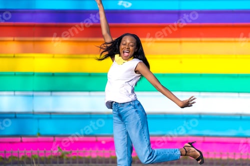 Preview: Cool young african woman jumping in an urban park