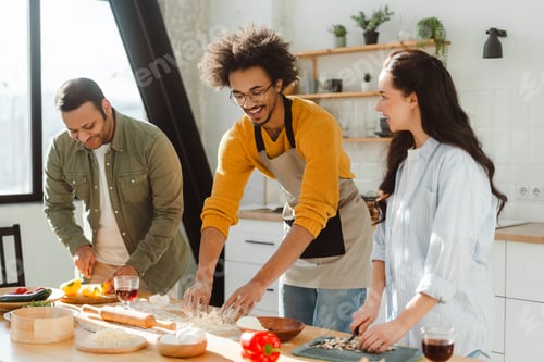 Preview: Smiling friends men and cheerful woman cooking together, making pizza, knead dough in modern kitchen