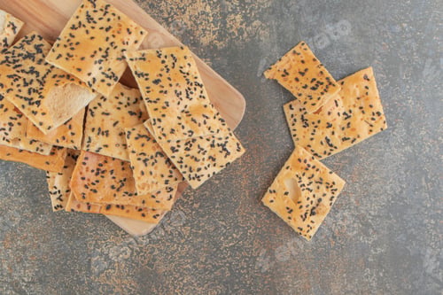 Preview: Pile of tandoori bread slices with sesame seeds on a board on blue background