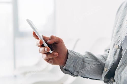 Cropped view employee using smartphone in office