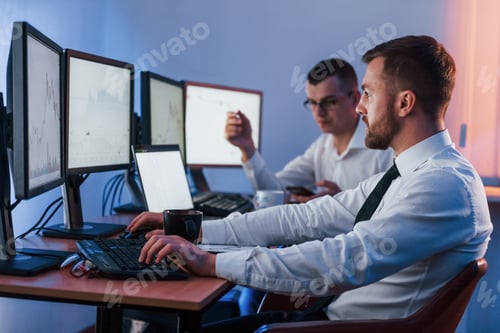 Preview: Side view. Two stock traders working in the office with exchange technology