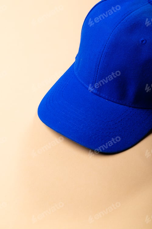 Preview: Composition of traditional peaked blue baseball cap on pale brown background