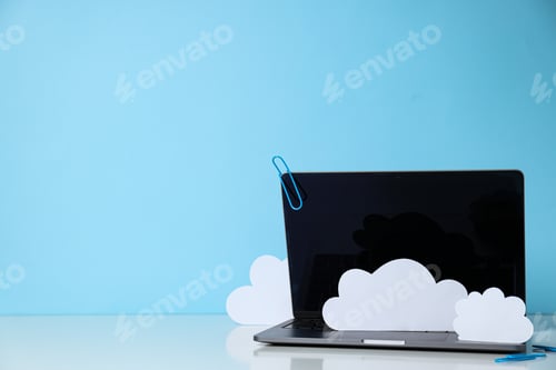 Preview: Laptop with paper clouds on a blue background, place for text