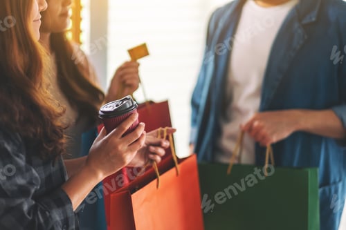 Preview: Group of people with shopping bags holding and using a credit card for purchasing