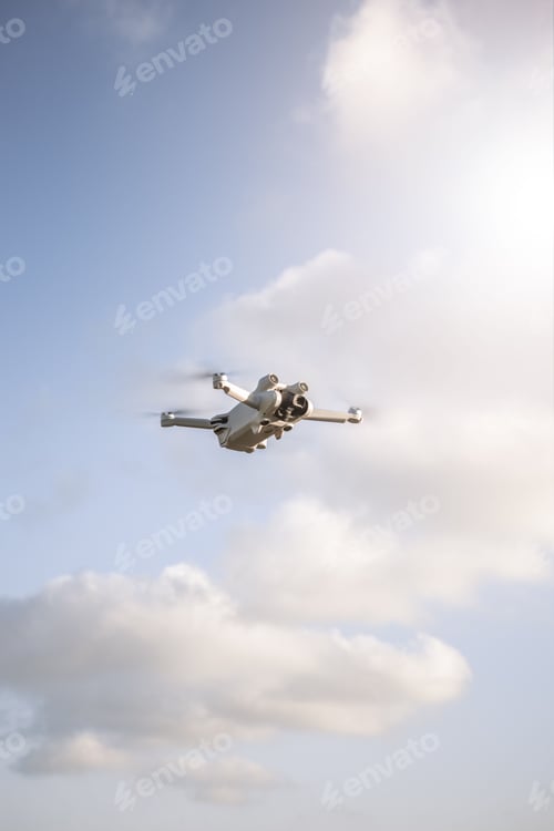 Preview: Vertical shot of a quadcopter flying in the sky in a sunny day