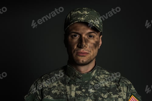 Preview: military man with dirt on face standing in uniform and cap isolated on grey