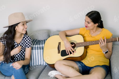 Preview: Two young women playing guitar on a couch