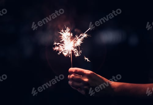 Preview: Hand holding burning Sparkler blast on a black background at night,holiday celebration party