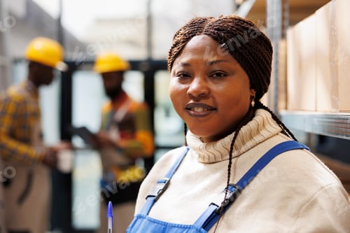 Preview: Smiling african american woman working in industrial warehouse portrait