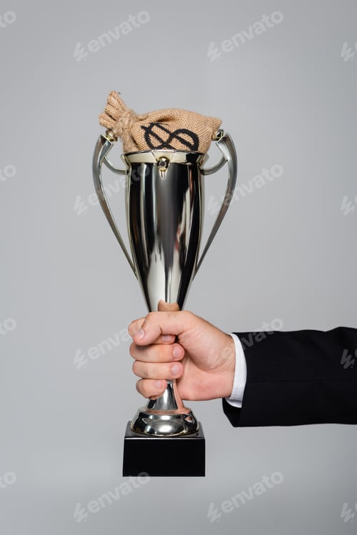 Preview: cropped view of man holding trophy with money bag isolated on grey