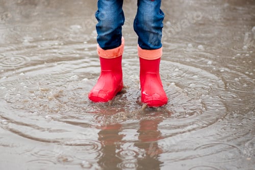 Preview: A cute little girl red boots jump in puddles and has a fun. Happy childhood. Early spring. Emotions.