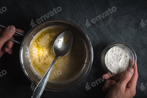 Preview: Melted butter in a ladle and a bowl of flour in a hand