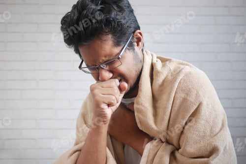 Preview: Mature man in blanket coughing while sited on bed