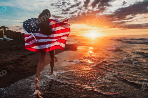 Preview: Happy woman smiling and running on beach with the US flag. July 4th independence day. Holiday