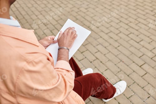 Preview: cropped view of indian disabled man in jacket sitting on bench and reading braille code, blind