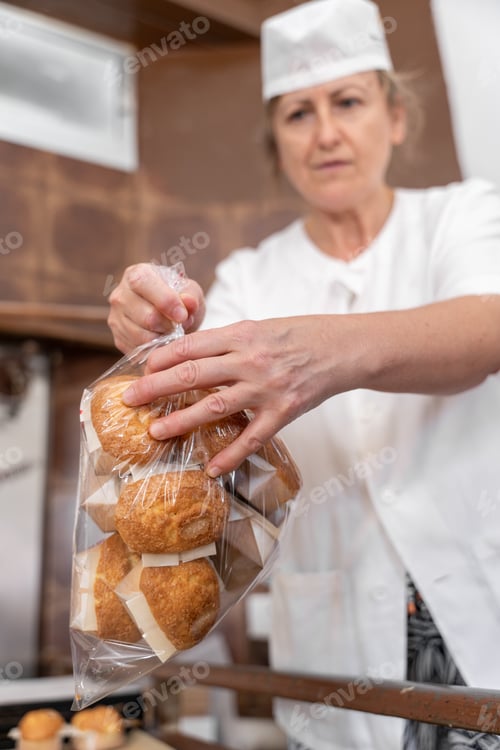 Preview: A baker woman is packing some fresh baked cupcakes into a plastic bag