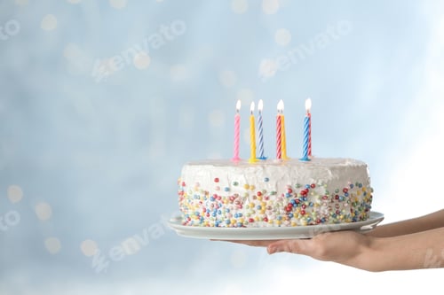 Preview: Woman holding birthday cake with burning candles against blurred background, closeup. Space for text