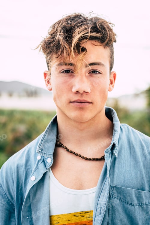 Preview: close up and portrait of millennial boy or teenager seriously looking at the camera