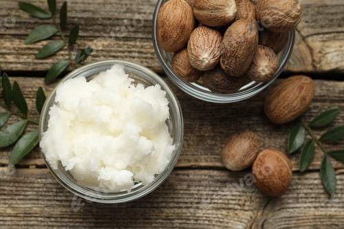 Preview: Natural shea butter, nuts and leaves on wooden table, flat lay