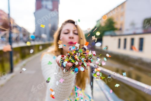 Preview: Young woman playing confetti outdoor