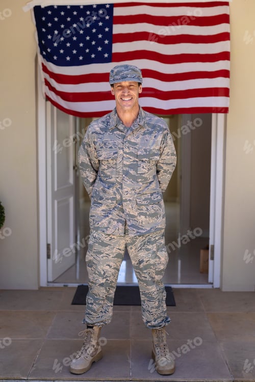 Preview: Full length portrait of smiling caucasian army soldier standing against usa flag at entrance