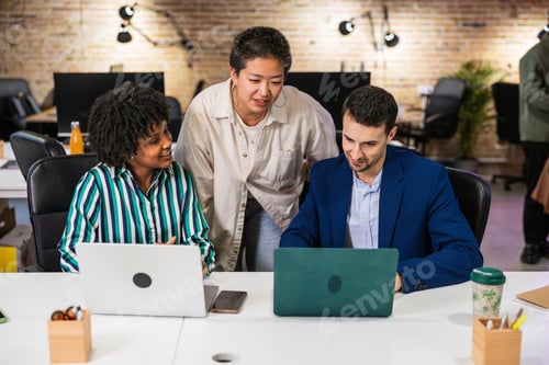 Preview: Multi ethnic team collaborating on project using laptops in modern office
