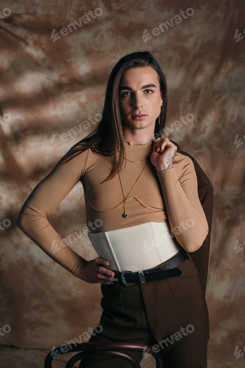 Preview: Fashionable queer person in corset holding blazer on abstract brown background