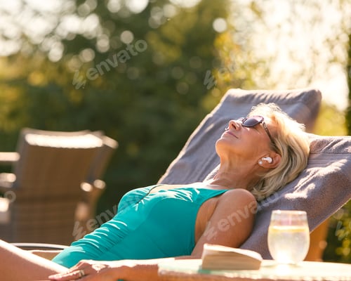 Preview: Senior Woman On Holiday In Swimming Costume Wearing Wireless Earbuds By Hotel Swimming Pool