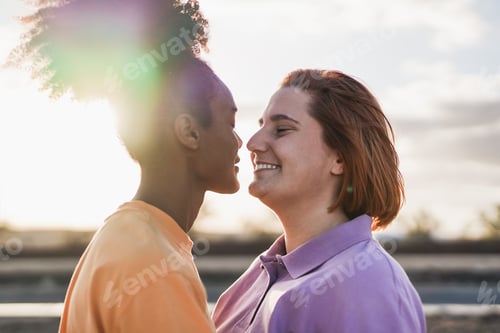 Preview: Multiethnic lesbian couple having tender moment at sunset outdoor