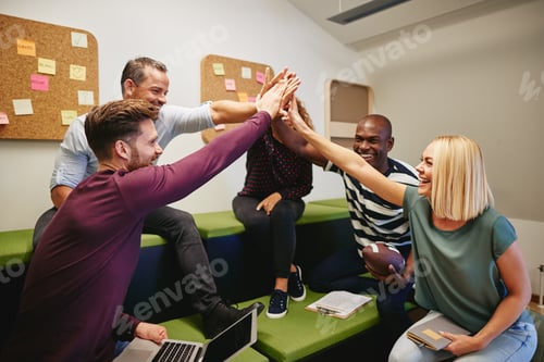 Preview: Laughing group of designers high fiving during an office meeting