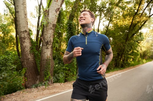Preview: Handsome young man enjoys a refreshing jog along a tree lined path in the morning sunlight