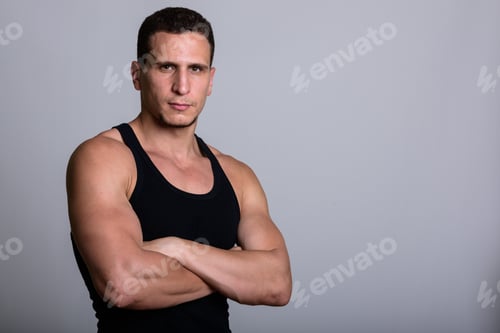 Preview: Studio shot of young muscular Persian man with arms crossed agai