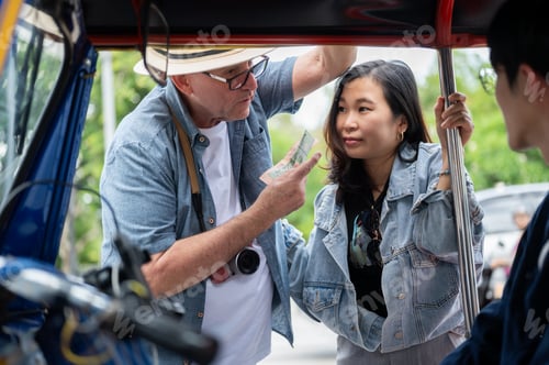 Preview: Old white man talking with wife as paying fare after riding in tuk tuk three wheel taxi touring city