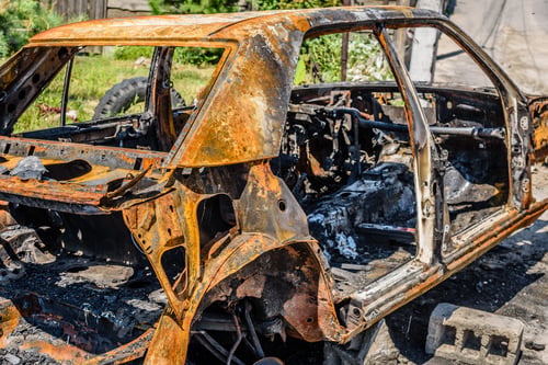 Preview: Burnt passenger car on the street of a dysfunctional area