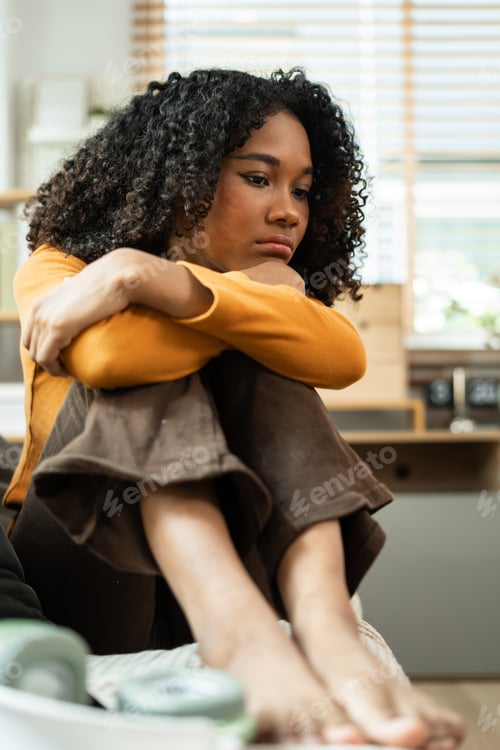 Preview: Depressed woman sitting next to the sofa sad, feeling tired, lonely and unhappy.