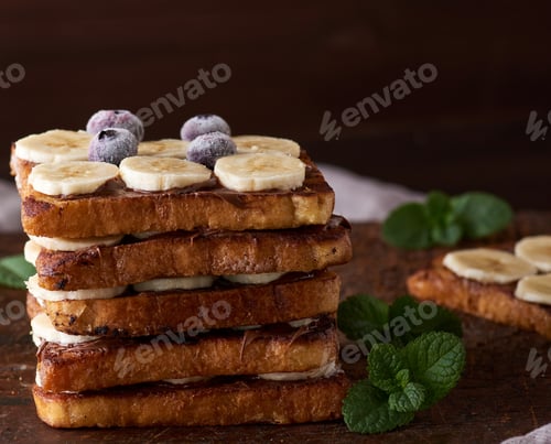 Preview: Pile of square fried bread slices with chocolate and banana slices