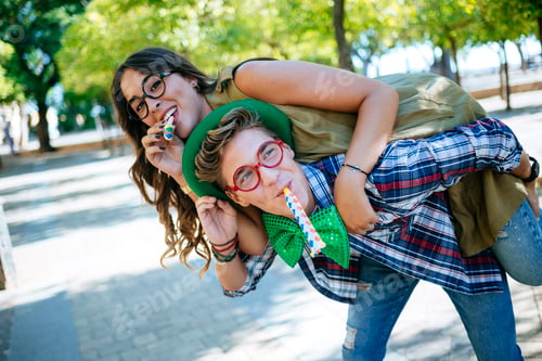 Preview: Couple celebrating saint patrick's day blowing party blowers outdoors