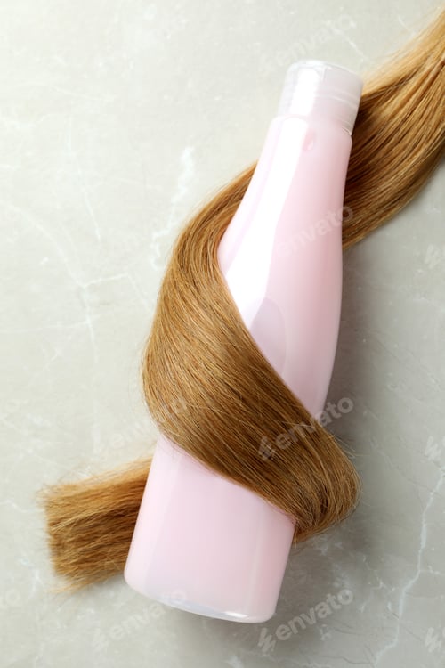 Preview: A lock of female hair with shampoo bottle