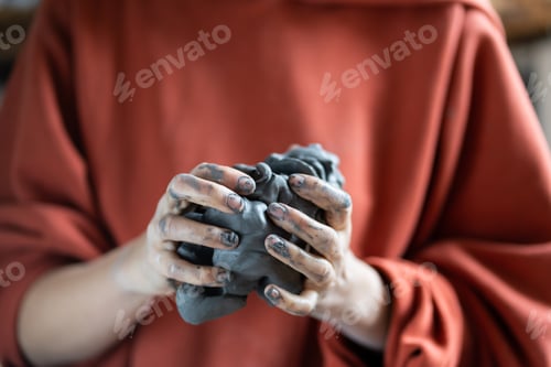 Preview: Woman holding piece of clay while visiting pottery master class, learning how to make ceramics
