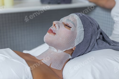 Preview: Woman in the spa salon is relaxing during the skin care treatment with gauzes in her face