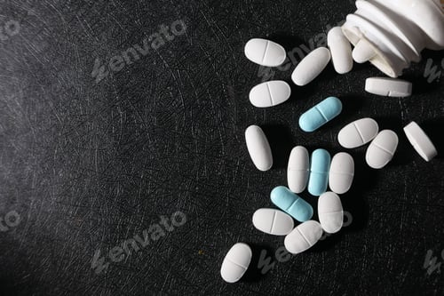 Preview: A variety of scattered pills and tablets displayed on a dark and textured surface