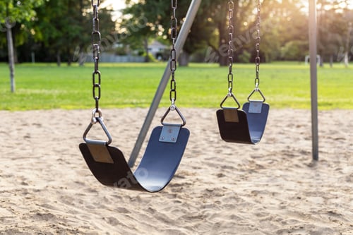 Preview: Playground for children with swings in the public park near school yard during sunset.