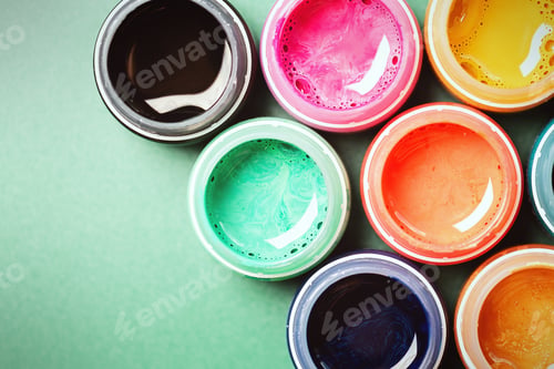 Preview: Mother-of-pearl, multi colored open cans of paint on a green background. The concept of creativity.