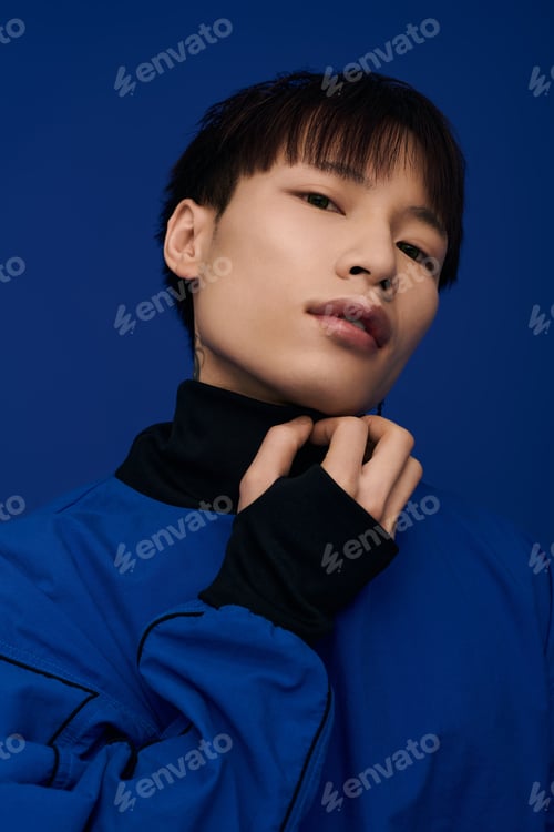 Preview: Captivating young asian man in striking blue attire posing elegantly against a bold background