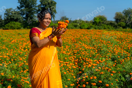 Preview: Indian woman in marigold field and enjoying nature.