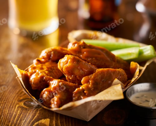 Preview: pile of tasty buffalo chicken wings in paper tray with celery and beer
