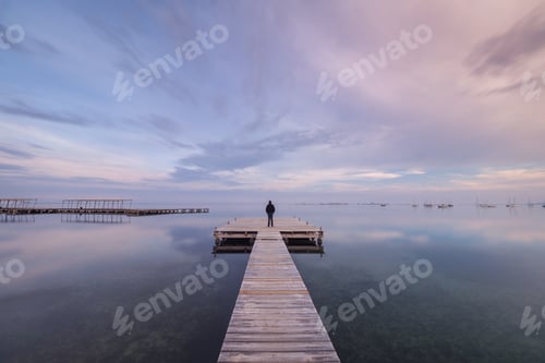 Preview: Anonymous person on wooden pier on cloudy evening