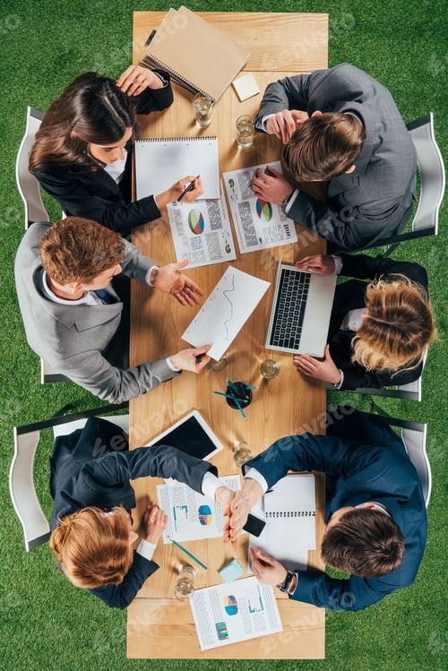 Preview: Top view of business colleagues having meeting at table with documents and devices in office
