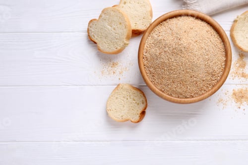 Preview: Fresh breadcrumbs in bowl on white wooden table, flat lay. Space for text